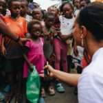 Humanitarian worker distributes aid to African children during community outreach in underserved area